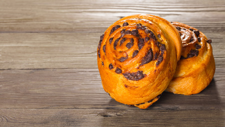 Fresh baked bun with chocolate on a wooden backgroundの写真素材