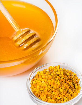 honey with a wooden stick close-up on white backgroundの写真素材