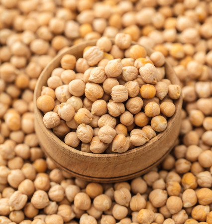 wooden bowl on a background of chickpeas closeupの写真素材