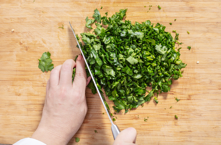 hand chopping parsley on wooden board closeupの写真素材