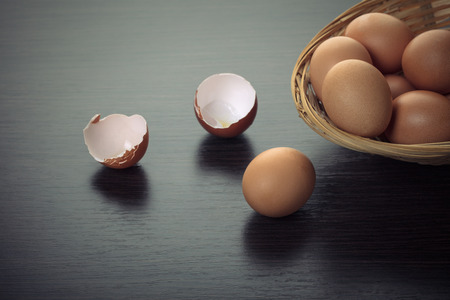 chicken eggs in a wicker bowl on a wooden background
