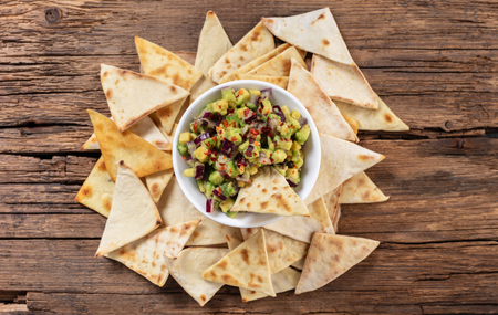 guacamole with corn chips closeup on wooden background