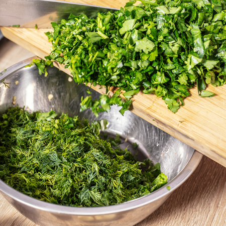 chopped parsley is poured into a bowl close-upの写真素材