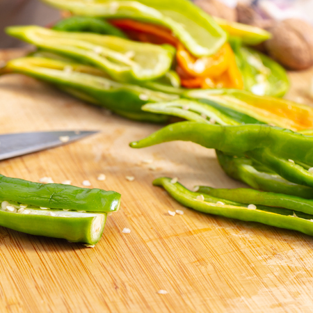 cook cutting hot peppers on a wooden board