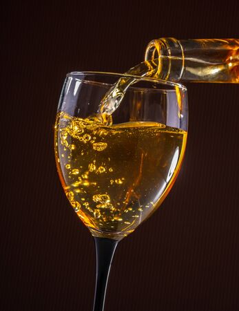 white wine pouring glass on brown backgroundの写真素材