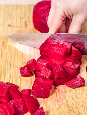 cook cuts red beet on a wooden board, preparation for cookingの写真素材