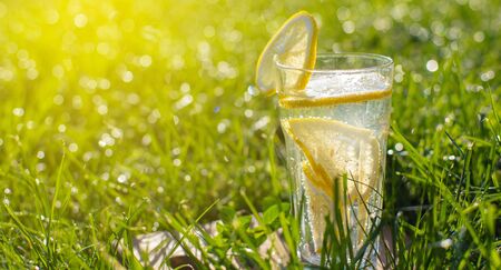 cold drink, lemonade in a glass on green grassの写真素材