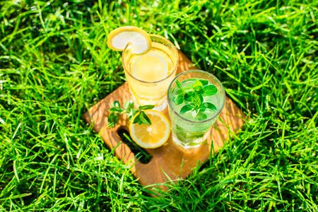 cold drink, lemonade in a glass on green grassの写真素材
