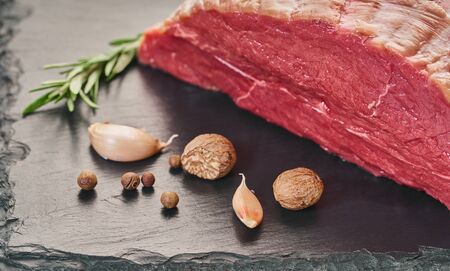 fresh raw meat with spices on black stone board
