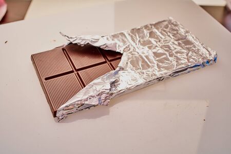 chocolate bar in foil on a white backgroundの写真素材