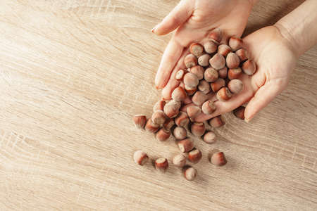 shelled hazelnuts in hands on a wooden backgroundの写真素材