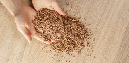 raw buckwheat in hands on wooden backgroundの写真素材