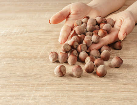 shelled hazelnuts in hands on a wooden backgroundの写真素材