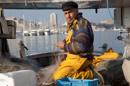 MARSEILLE, FRANCE,  MARCH 6: a fisherman, on the knees in his boat, in the Vieux-Port, tidies up his nets, on Sunday, March 6th, 2011 in Marseille, France.のeditorial素材