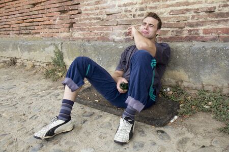 Drunk homeless man is sitting in the street 
