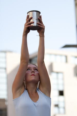 AURILLAC, FRANCE - AUGUST 22: a teen raises her arms to hold a carafe as part of the Aurillac International Street Theater Festival,show by the Company Rebus ,on august 22, 2012, in Aurillac,France.のeditorial素材