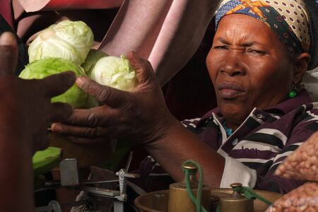 Praia, Cape Verde - December 6, 2012: An old woman is selling salads. This African vendor is looking at the camera.. のeditorial素材