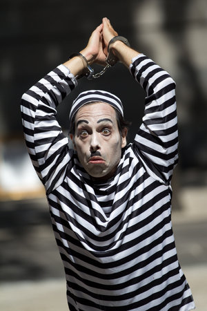 AURILLAC, FRANCE - AUGUST 21  a handcuffed clown wears  a striped costume as part of the Aurillac International Street Theater Festival, Cie Les hommes papillon,on august 21, 2013, in Aurillac,France のeditorial素材