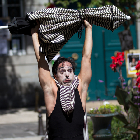 AURILLAC, FRANCE - AUGUST 21  a funny actor carries a striped parasol as part of the Aurillac International Street Theater Festival, Company Les hommes papillon,on august 21, 2013, in Aurillac,France のeditorial素材