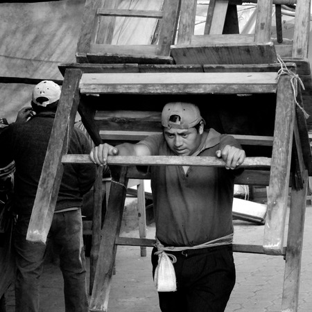 CHICHICASTENANGO, GUATEMALA -  DECEMBER 1  A man is carrying  a big wooden table and some chairs on his back to the market , on December 1, 2013, in Chichicastenango, Guatemala  のeditorial素材