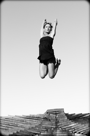 Female dancer jumping in the air above a heap of planks の写真素材