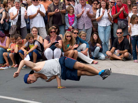 AURILLAC, FRANCE, AUGUST 22: Spectators look at a young breakdancer in the street as share of the...