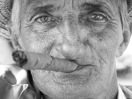VINALES, CUBA - NOVEMBER 16: portrait of an old man wearing a straw hat and smoking a cuban cigar...