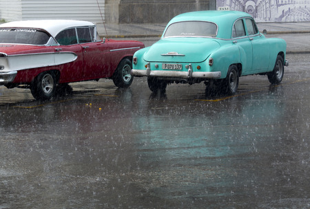 HAVANA, CUBA - NOVEMBER 21: two vintage american car parked in the city center under a big rain, we november 21, 2014, in Havana, Cuba.のeditorial素材