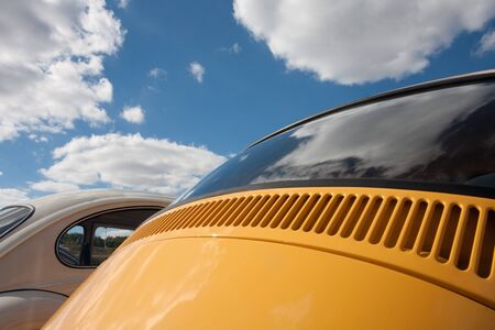 Sunny and cloudy sky over a rear view of two old cars. You can see only a portion of the bodies.の写真素材