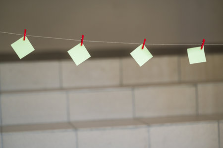 Blank sticky notes hanging on clothesline with space for text.