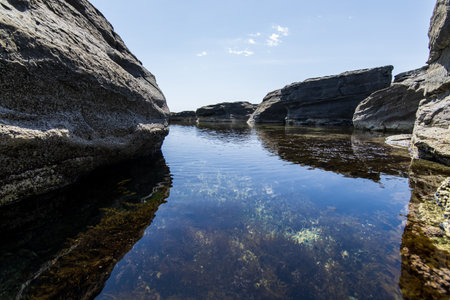 Rocky beach with crystal clear water and reflections in the water.