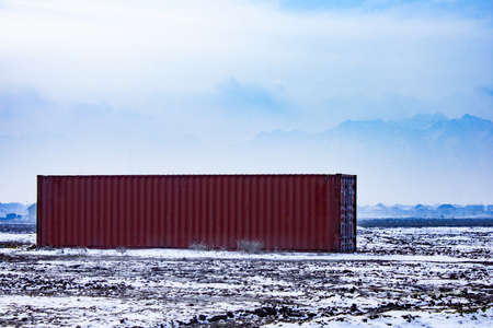The container cargo in the middle of a field with mountains in the backgroundの写真素材