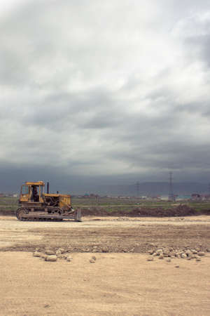 Yellow bulldozer on tracks at the mountain road construction