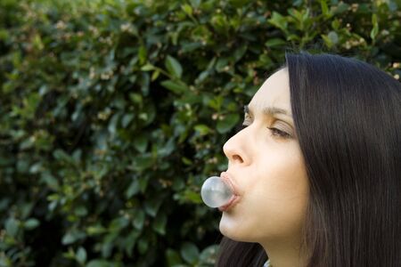 Girl in front of a green leaf blowing bubbleの写真素材