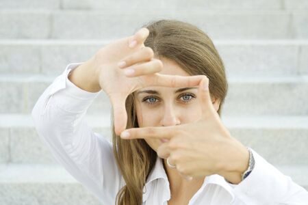Young businesswoman looks through a frame made of hand