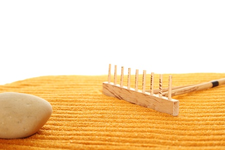 On the golden (orange) sand with wooden rakes made strips. Beside these wooden rakes. Rake in Zen Garden taken closeupの写真素材