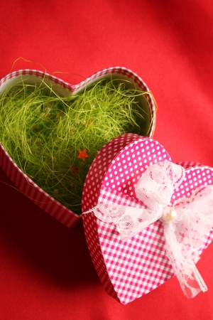 Large gift box in heart shape on red fabric の写真素材