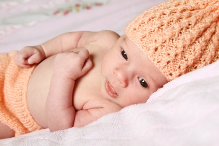 Close-up of a baby lying in a knitted hat and shorts