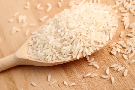 Close-up of rice in a wooden spoon on a wooden surface