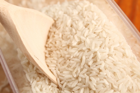 Close-up of rice in a wooden spoon on a wooden surface