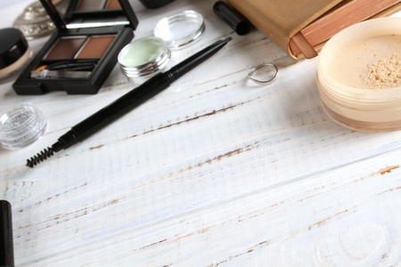 Decorative cosmetics lipstick, eye shadow, pencil and other cosmetics on a wooden white background.