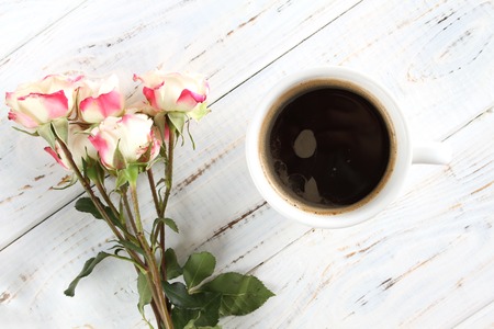 Coffee in a white cup near white roses. Romantic breakfast.の写真素材