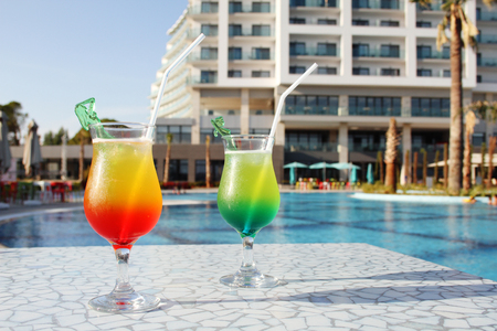 Two glasses with colored cocktails are around the poolのeditorial素材