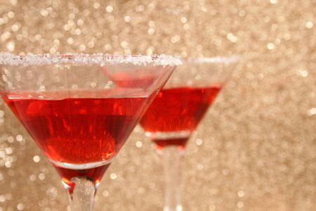 Two glasses with a red cocktail. Background from gold spangles.の写真素材