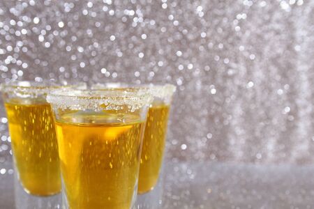 Glasses with a yellow drink. Background from silver spangles.の写真素材