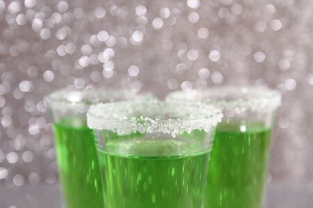 Three glasses with green alcoholic drinks. Background silver shinyの写真素材