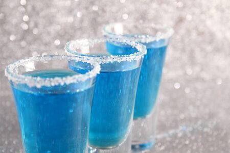 Three glasses with blue alcoholic drinks. Stand on a silver shiny background.の写真素材
