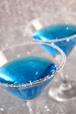 Two glasses with blue alcoholic drinks. Stand on a silver shiny background.の写真素材