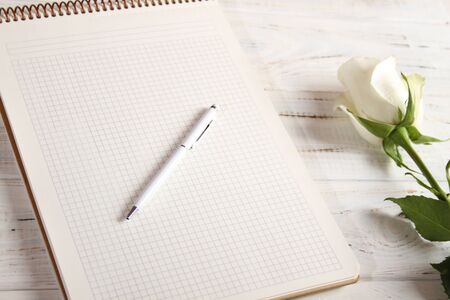 A large notebook with a white pen and a beautiful white rose.の写真素材