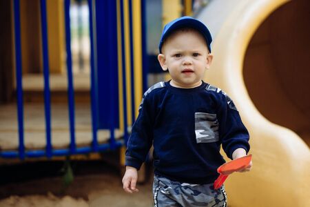 Seriously boy in the cap goes with the toys , portrait, playrgoundの写真素材